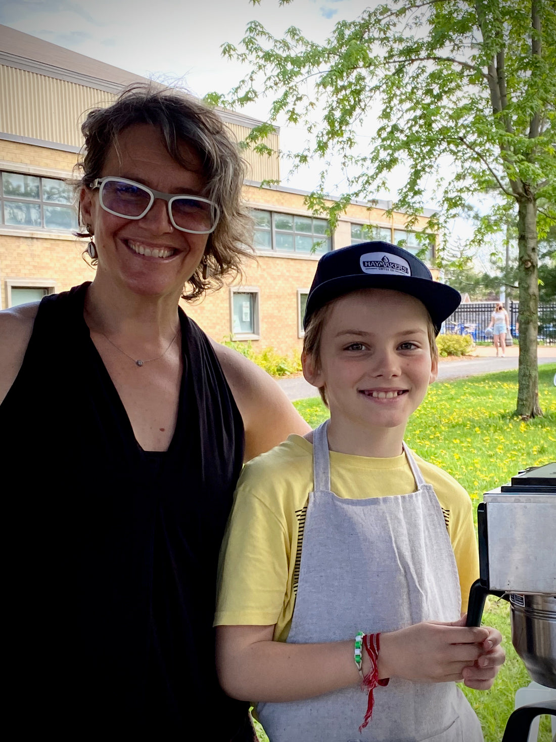 Haymakers Coffee owner Alix with son Scout standing together at the booth at Memorial Centre Market brewing hot coffee and selling fresh roasted single origin, microlot coffee beans.